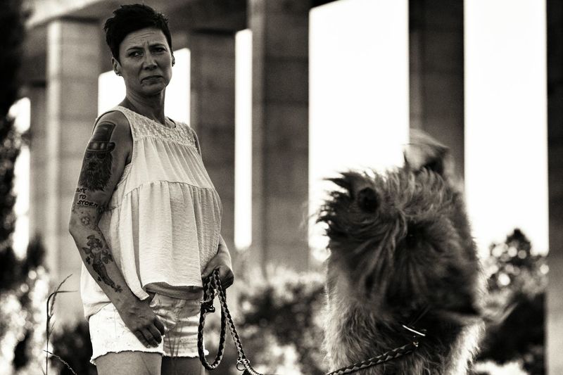 Woman standing by irish wolfhound shaking against columns