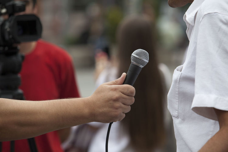 Cropped hand of journalist holding microphone for woman