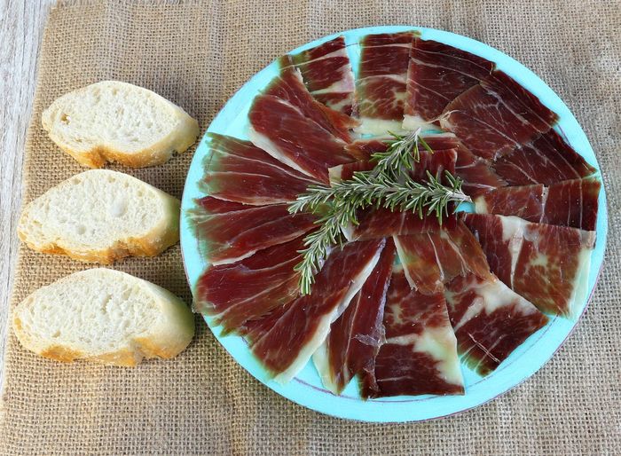 High angle view of ham on blue plate and some pieces of bread