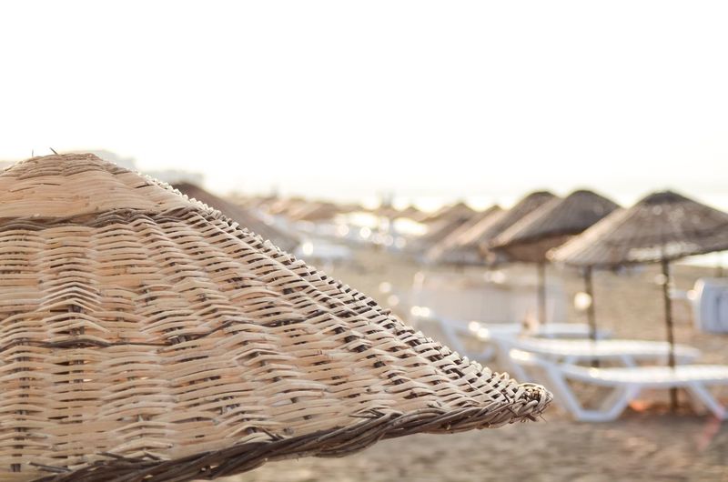 Close-up of wicker basket on beach against clear sky