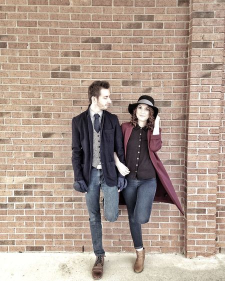 Full length of young couple standing against brick wall