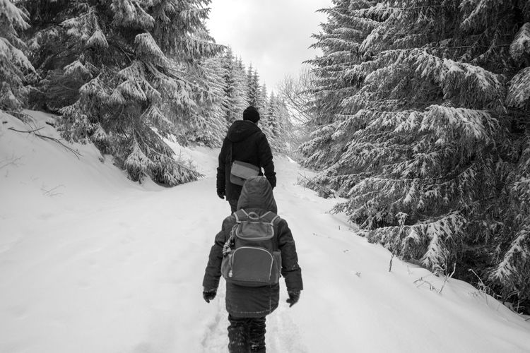 Rear view of man and kid on snow covered landscape