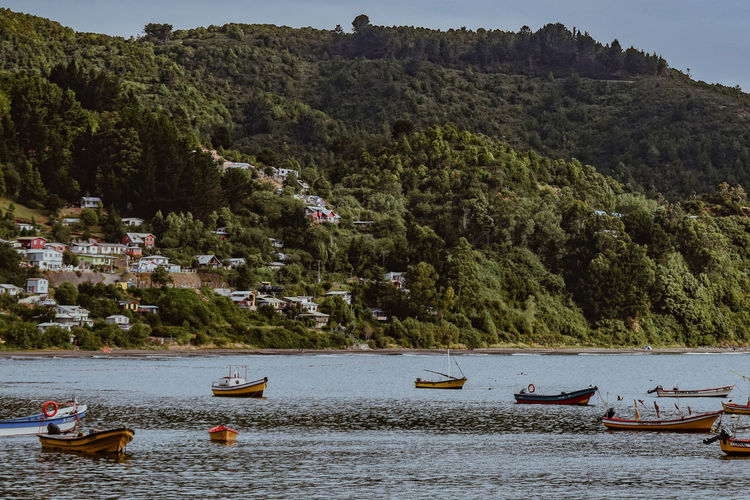 Boats moored on river by mountains