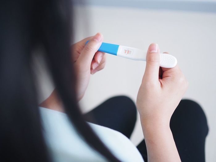 Woman holding pregnancy test at home