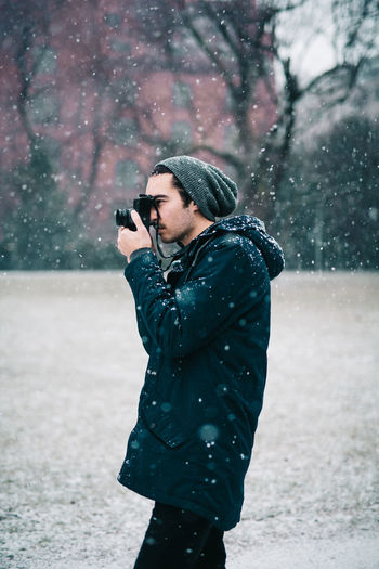 Man photographing in snow on street in city