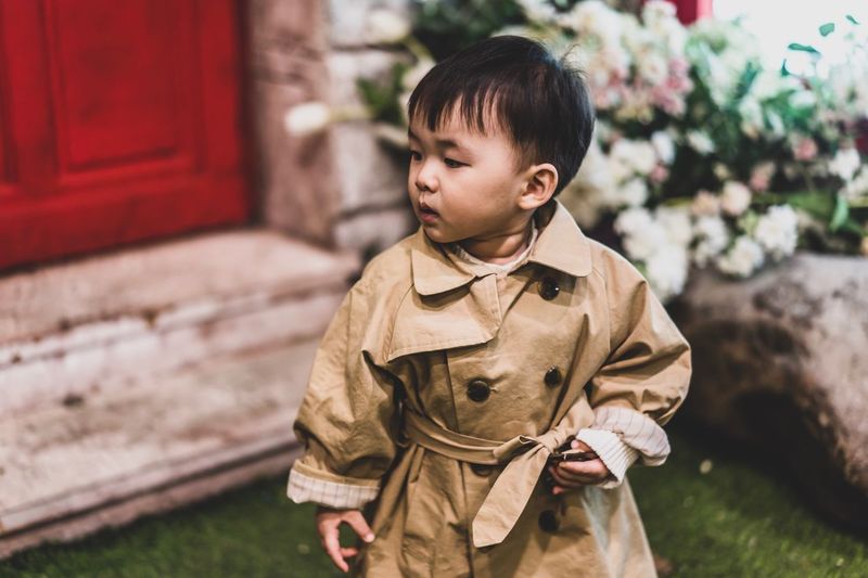 Baby boy wearing trench coat looking away