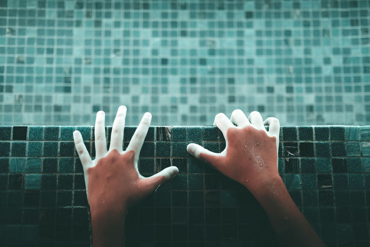 Directly above shot of hands in illuminated swimming pool