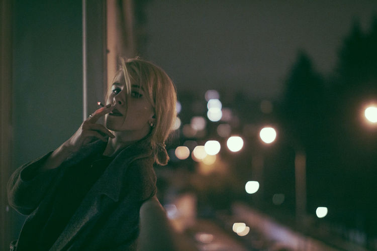Portrait of woman looking at illuminated lights at night