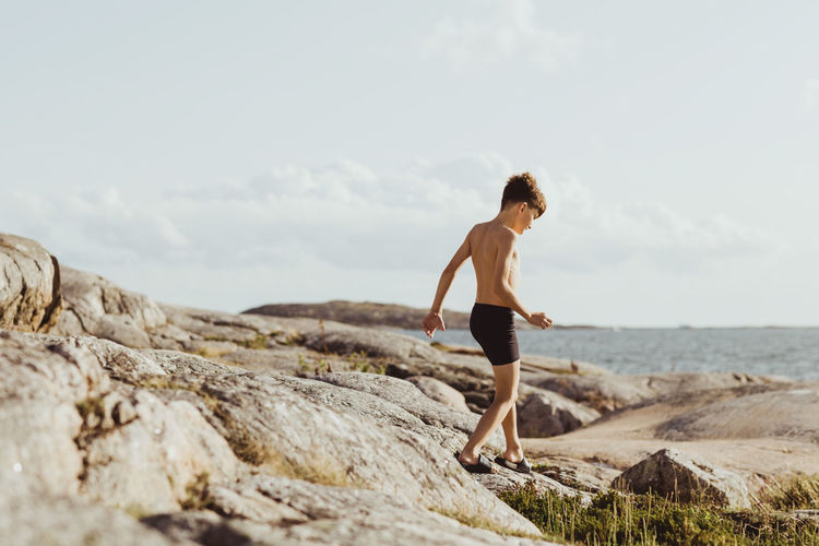 Shirtless boy walking on archipelago during weekend