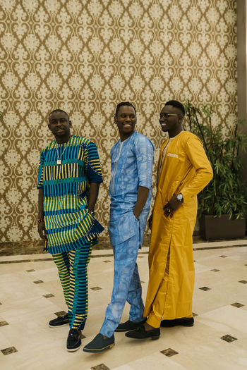 Smiling men standing with hands in pockets at banquet