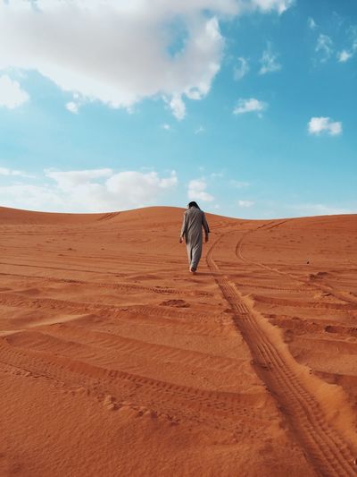 Rear view of man walking on desert
