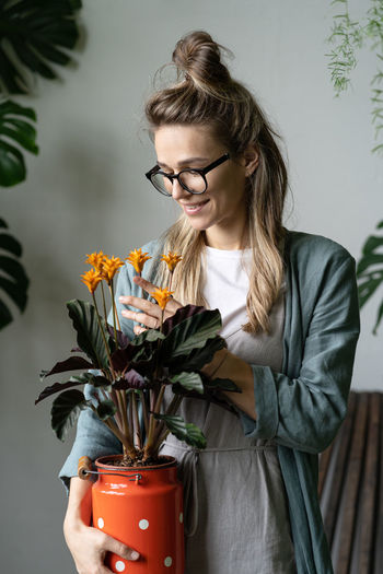 Beautiful woman standing by potted plant