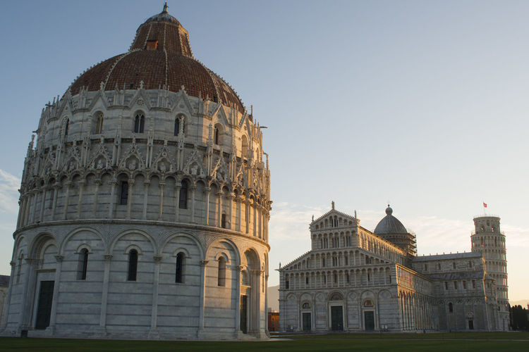 Pisa baptistery on field against sky in city