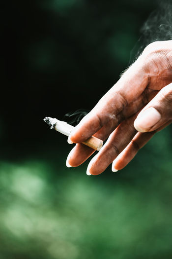 Close-up of cropped hand holding cigarette