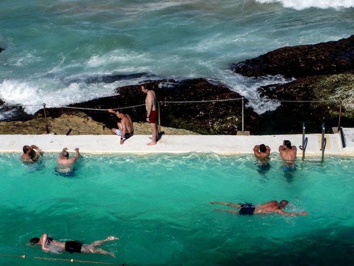 People in swimming pool against calm sea