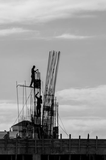 Silhouette crane at construction site against sky