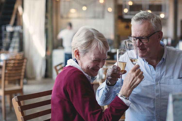 Loving senior man and woman enjoying champagne in restaurant