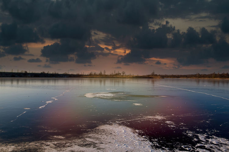 Scenic view of frozen lake against sky at sunset