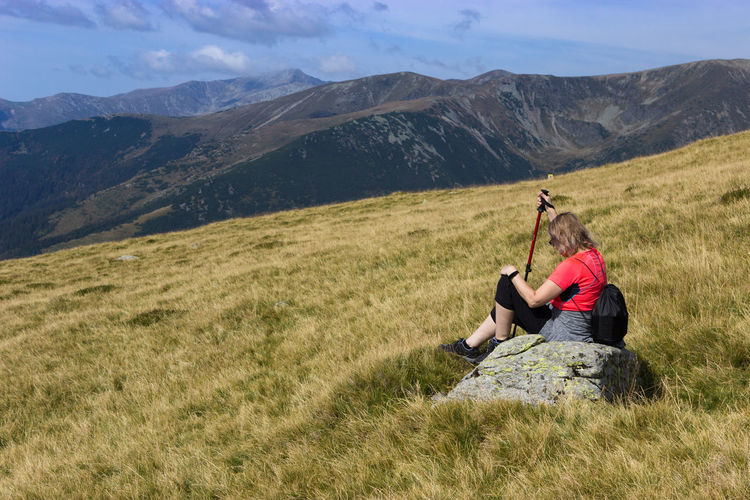 Rear view of woman sitting on field against sky