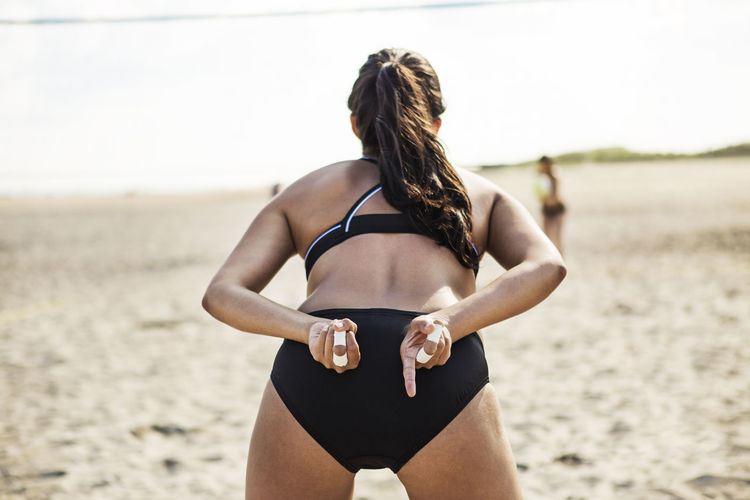 Rear view of woman standing at beach while playing volleyball