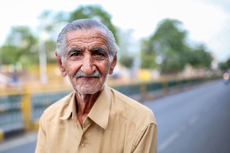 Portrait of senior man standing on road against sky