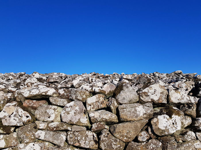 Top of dry stone wall against blue sky