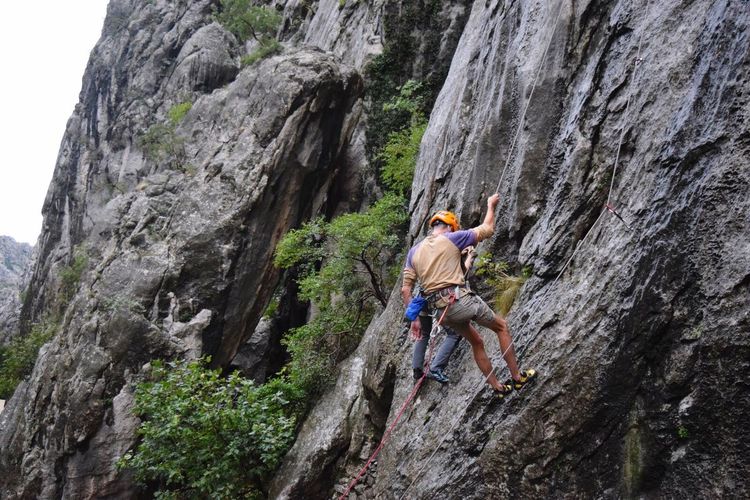 Low angle view of men rock climbing mountain
