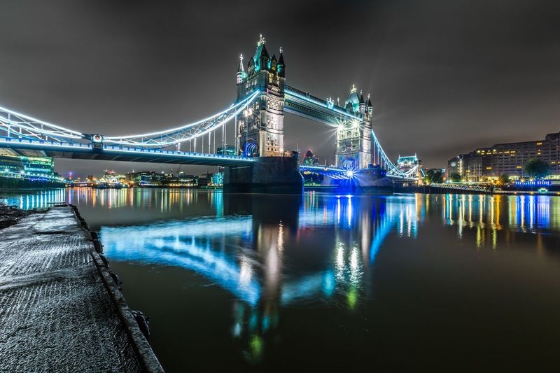 Illuminated tower bridge over thames river in city at night