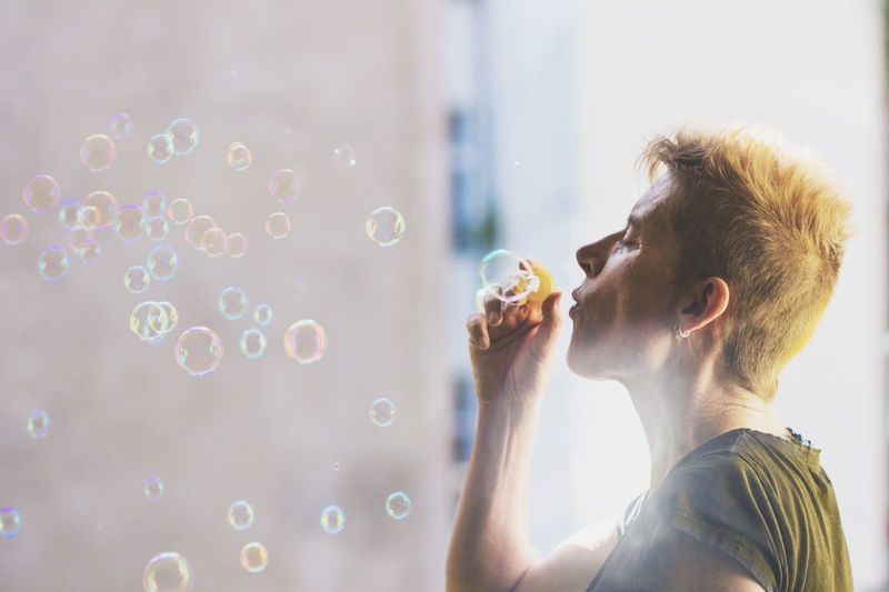 Profile view of mature woman blowing bubbles