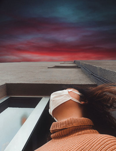 Low angle view of woman wearing mask looking away outdoors