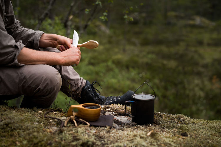 Man whittling a spoon in the forest.