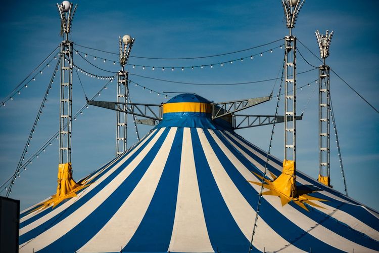 Low angle view of circus tent against blue sky