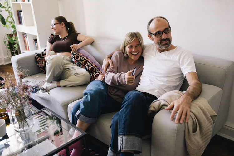 Man sitting with woman and daughter on sofa at home