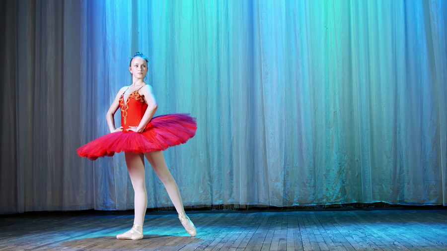 Ballet rehearsal, on the stage of the old theater hall. young ballerina in red ballet tutu