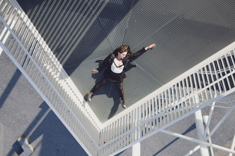 High angle view of young woman lying down on elevated walkway