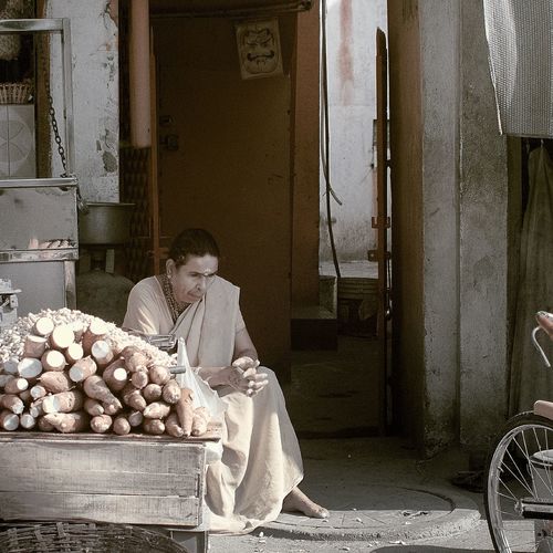 Mature woman selling sweet potatoes at street market