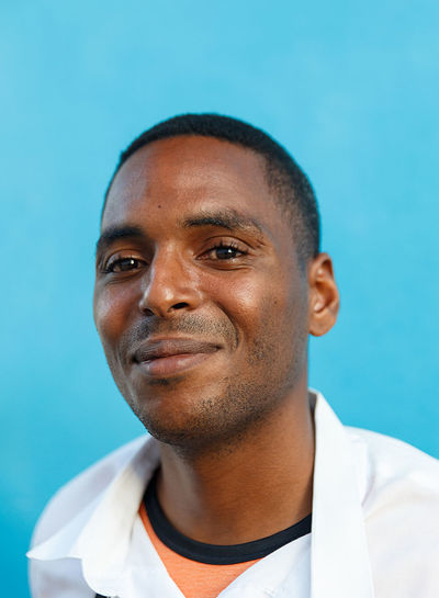 Close-up portrait of smiling young man against blue background
