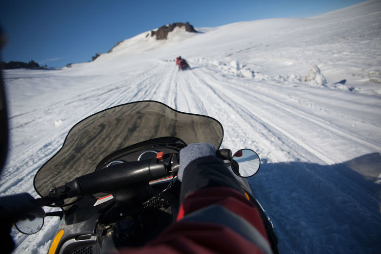Cropped image of person riding on snowmobile