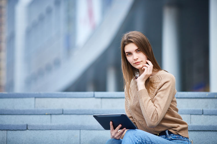 Portrait of young woman looking away while sitting outdoors