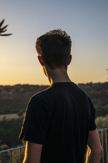 Rear view of man looking at sunset