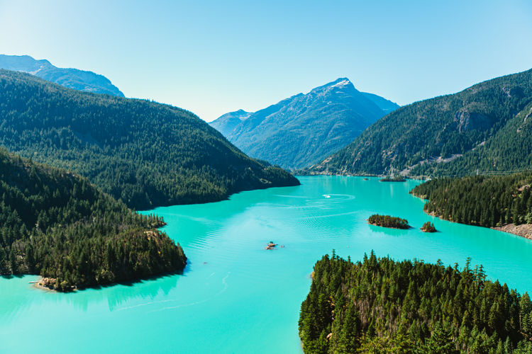 Scenic view of lake and mountains against clear blue sky