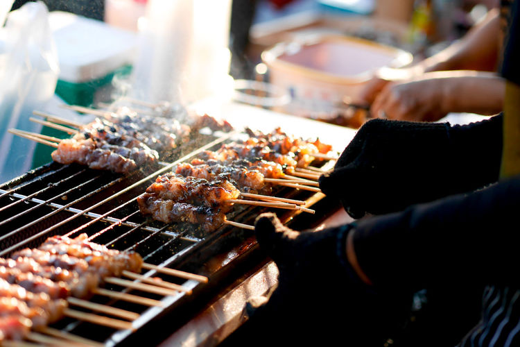 Cropped hands of man cooking food on barbecue grill