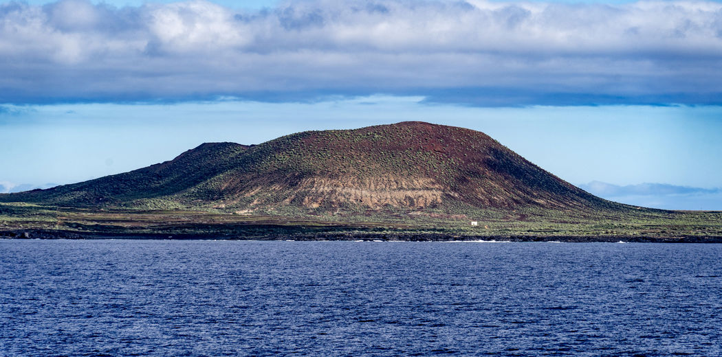 Scenic view of sea and mountains against sky