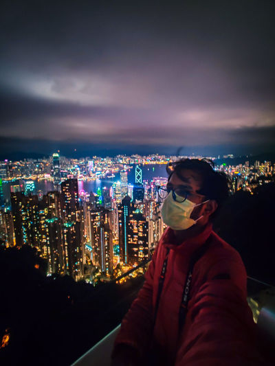 Woman standing by illuminated buildings against sky at night