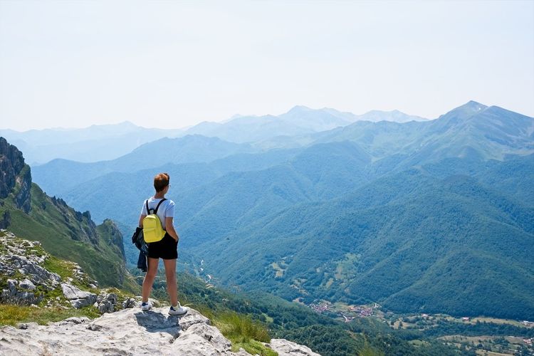 A woman looks at the landscape from the top of a mountain