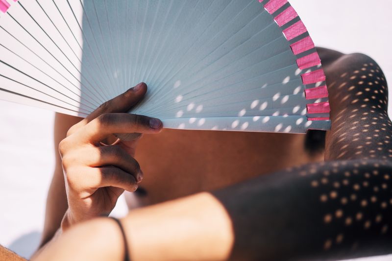Midsection of shirtless teenage boy holding folding fan