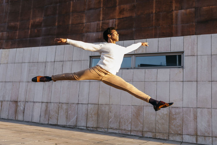 Full length of young man jumping against built structure