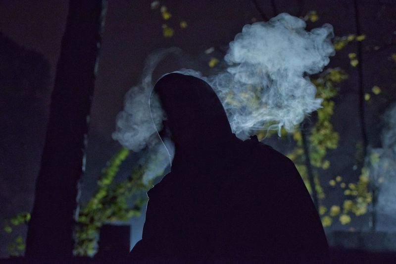 Close-up of man smoking against sky during winter