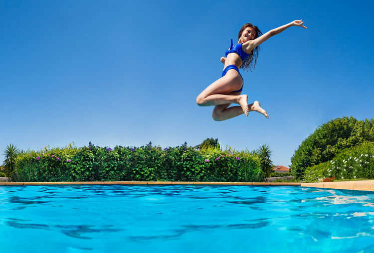 Full length of woman jumping in swimming pool