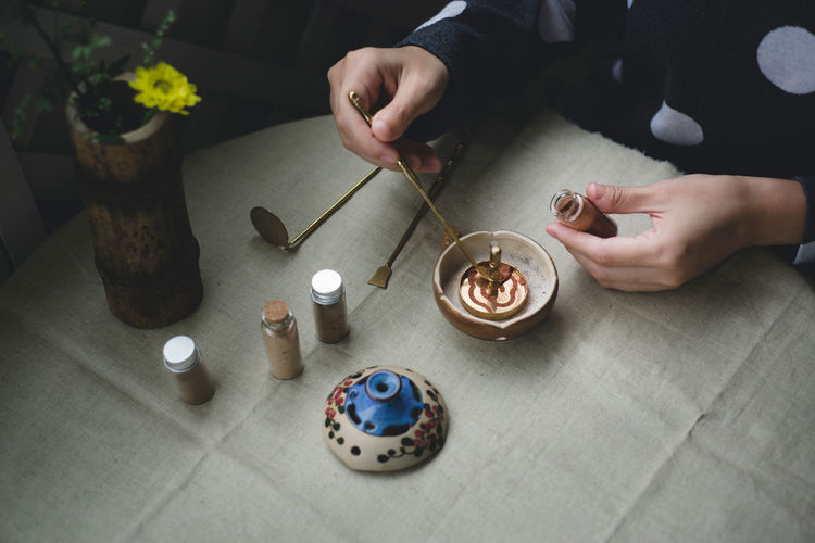 Midsection of man making incense on table